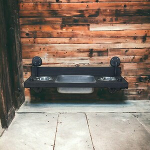 Floating water bin dual feeder: steampunk pet feeding station with two stainless bowls on a wooden platform beside a dog.