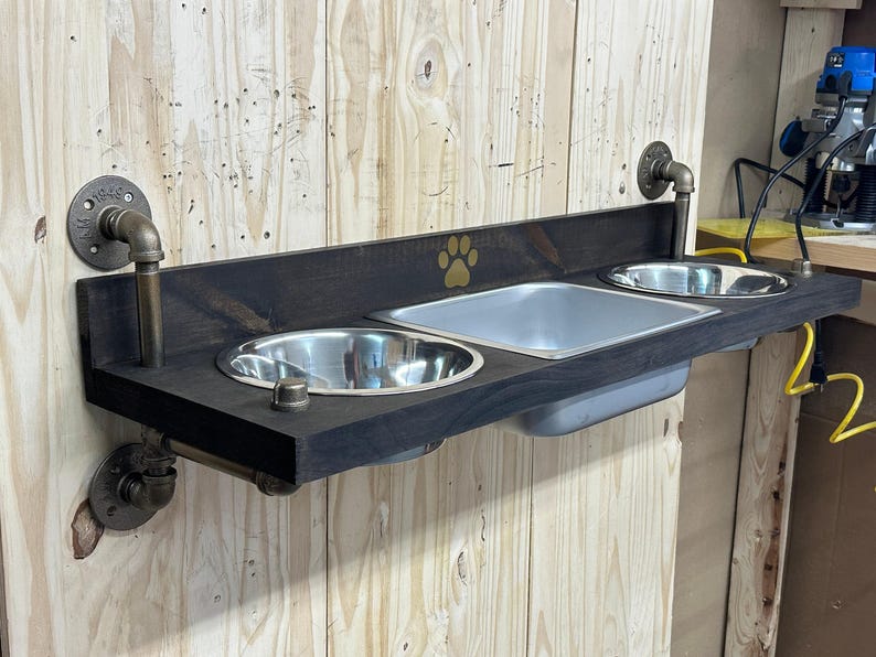 Floating water bin dual feeder: steampunk pet feeding station with two stainless bowls on a wooden platform beside a dog.