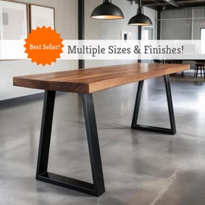 May include: A rectangular wooden table with a dark brown finish and black metal legs. The table has a modern design and is suitable for various uses. Text on the image reads: "Best Seller! Multiple Sizes & Finishes!"