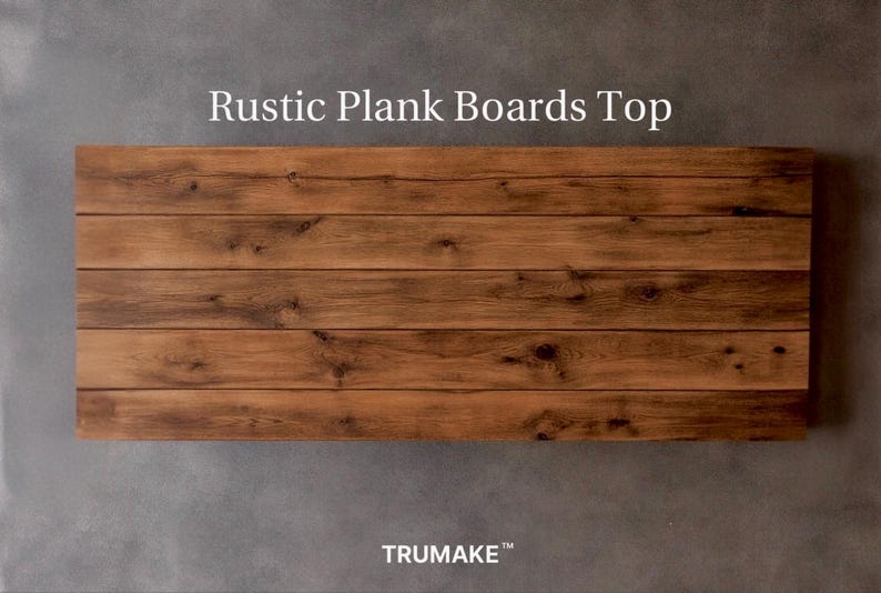 May include: A rectangular tabletop surface composed of five horizontal brown wooden planks with visible grain patterns and knots. The text "Rustic Plank Boards Top" is printed above the wood, and the text "TRUMAKE&trade;" is printed below the wood.