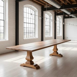 May include: A long, rectangular wooden dining table featuring a smooth, natural brown finish and a flat tabletop surface. The table is supported by two substantial, carved pedestal bases with tiered, square-shaped feet, providing a stable foundation.