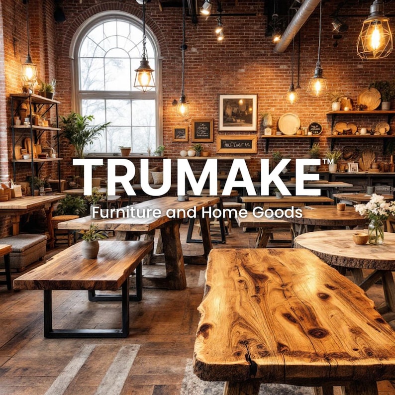 May include: Interior shot of a furniture store with wooden tables and shelves. The store features exposed brick walls, large windows, and hanging light fixtures. The store's name, TRUMAKE, is displayed prominently, along with the tagline "Furniture and Home Goods."