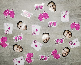 May include: Pink and white stickers with images of playing cards, dice, money, and faces. The stickers are on a gray background.