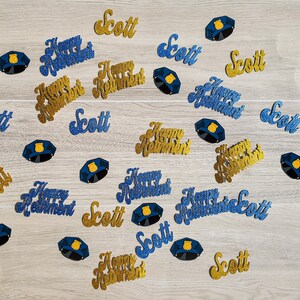 May include: Blue and gold glitter confetti with the words "Happy Retirement" and "Scott" repeated throughout.  There are also blue glitter police officer badges.