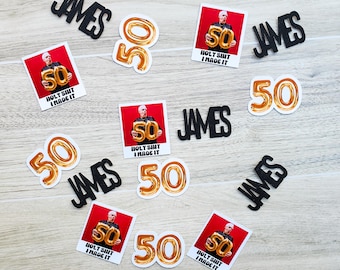 Könnte beinhalten: Eine Sammlung von schwarzen und goldenen Partydekorationen für eine 50. Geburtstagsparty. Die Dekorationen beinhalten den Namen "James" in schwarzen Buchstaben, goldene Nummer 50 Ballons und rote und weiße Fotobox-Requisiten mit dem Text "Holy Shit I Made It".