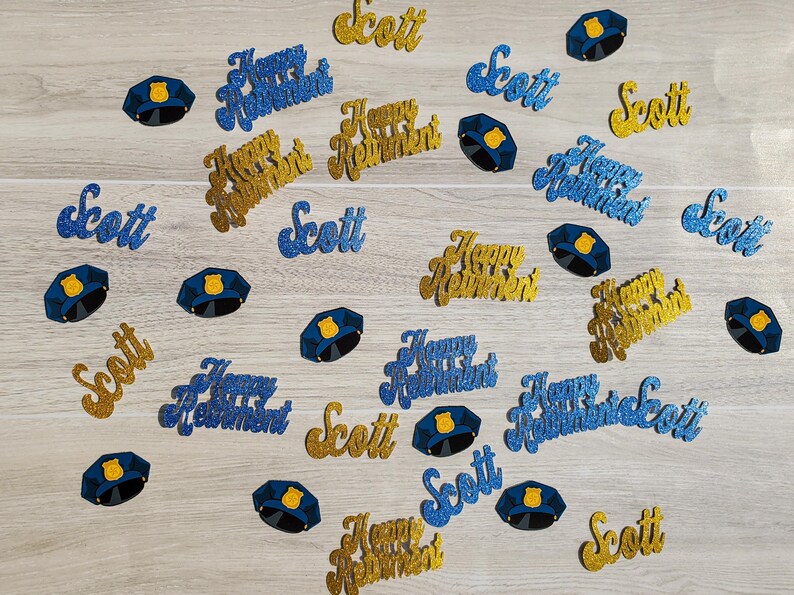May include: Blue and gold glitter confetti with the words "Happy Retirement" and "Scott". There are also blue glitter police officer hats.