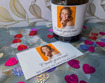 May include: A champagne bottle with a custom label featuring a woman's photo and the text "Create your own! Any saying, any name, for any event!". A matching card is next to the bottle, surrounded by heart-shaped confetti.