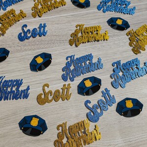 May include: Blue and gold glitter confetti with the text "Happy Retirement" and "Scott". There are also blue glitter police officer hats.