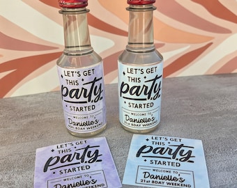 Könnte beinhalten: Zwei kleine Glasflaschen mit roten Verschlüssen und Etiketten mit der Aufschrift "Let's Get This Party Started". Ein Etikett lautet "Danielle's 40th Bday Weekend", das andere "Danielle's 21st Bday Weekend". Zwei passende Etiketten sind ebenfalls vorhanden.