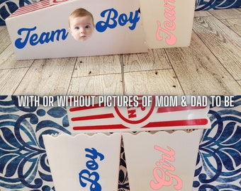 Könnte beinhalten: Zwei weiße Popcornbehälter mit blauem und rosa Text, der "Team Boy" und "Team Girl" lautet. Die Behälter sind mit roten und weißen Streifen verziert.