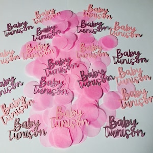 May include: Pink and white confetti with the text "Baby Tunison" printed on each piece.