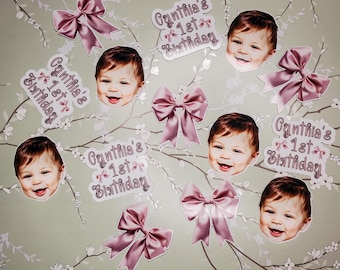 May include: Pink and white first birthday party decorations with a baby's photo and the text "Cynthia's 1st Birthday".