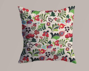 May include: Square decorative pillow with a floral pattern. The pillow features a cream-colored background with a repeating design of red, green, blue, and purple flowers and leaves. The design is symmetrical and covers the entire surface of the pillow.