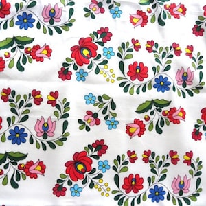 May include: White fabric with a repeating pattern of colorful flowers. The flowers are red, pink, blue, yellow, and green. The pattern is traditional and folk art inspired.
