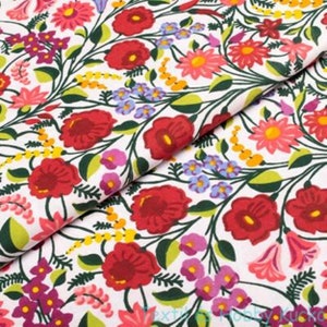 May include: White fabric with a colourful floral pattern. The design features red poppies, pink and yellow daisies, purple and blue wildflowers, and green leaves. The fabric is folded, showcasing the repeating botanical print.