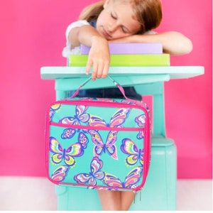 May include: A turquoise lunch bag with a pink zipper and handle. The bag has a colorful butterfly pattern.