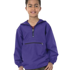 May include: A purple pull-over jacket with a zipper and a pocket. The jacket has a hood and is made of a lightweight material.