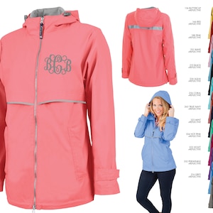 May include: A pink rain jacket with a reflective strip and a monogrammed design. The jacket has a hood and a zipper closure. The jacket is shown in various colors.