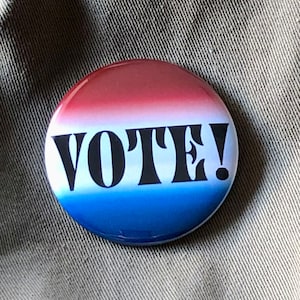 Peut inclure: Un bouton rouge, blanc et bleu avec le mot "VOTE!" en lettres noires.