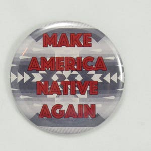 May include: A round button with a white and gray patterned background. The text "MAKE AMERICA NATIVE AGAIN" is printed in red.