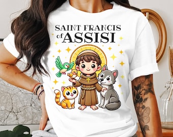 May include: White t-shirt featuring a cartoon illustration of Saint Francis of Assisi. The design includes a cartoon figure, a cat, a wolf, and birds. The text "SAINT FRANCIS of ASSISI" is printed at the top.