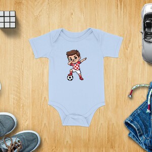 Baby onesie with a cartoon boy dabbling with a soccer ball.