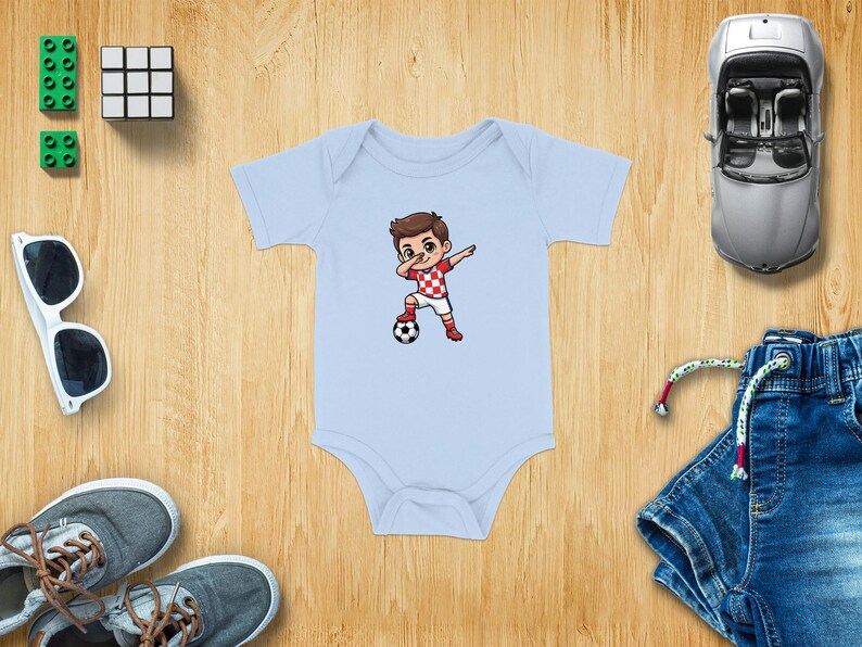 Baby onesie with a cartoon boy dabbling with a soccer ball.