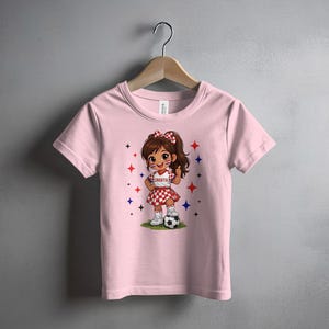 Pink t-shirt with cartoon girl in Croatian outfit holding a soccer ball.