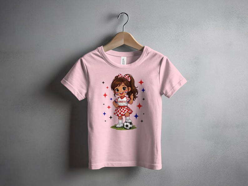 Pink t-shirt with cartoon girl in Croatian outfit holding a soccer ball.