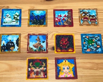 May include: Ten framed pixel art pieces featuring characters and scenes from the Super Mario Bros. video game series. The frames are all gold with a black border. The pixel art is colorful and detailed, with characters like Bowser, Peach, and Mario.