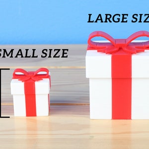 May include: Two white gift boxes with red ribbon and bows. The smaller box is 1.3 inches tall and the larger box is 2.5 inches tall.  SMALL SIZE and LARGE SIZE are written above the boxes.