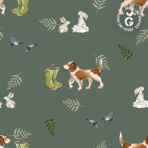 May include: A repeating pattern featuring watercolor illustrations of a dog, rabbits, birds, and green wellington boots on a muted green background. The design includes sprigs of leaves and a logo in the upper right corner.