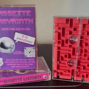 May include: A purple and pink cassette tape game titled "Cassette Labyrinth" with a silver ball maze. The game features the text "It is Amazeing!" and a QR code. A red maze game is also visible.