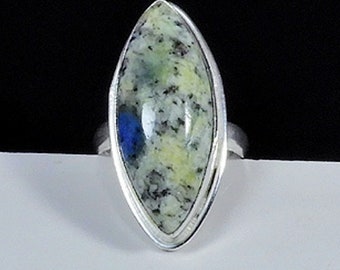 May include: A silver ring with a marbled green and blue gemstone set in a marquise shape.
