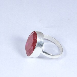 May include: A silver ring featuring a large, oval-shaped, pink gemstone.