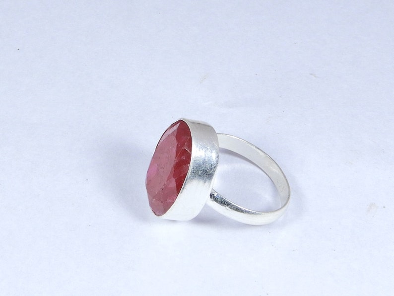May include: A silver ring featuring a large, oval-shaped, pink gemstone.