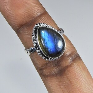 May include: A silver ring with a blue labradorite gemstone. The ring has a twisted band and a decorative setting around the stone.