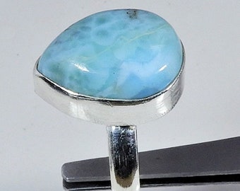 May include: A sterling silver ring featuring a pear-shaped, light blue larimar gemstone. The stone has a marbled appearance with shades of white and turquoise. The ring's band is a simple, polished silver.