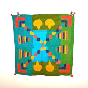 May include: A colourful quilt with a geometric pattern in shades of green, blue, yellow, orange, and pink. The quilt is made of squares and rectangles, and it has a unique design that is both modern and traditional.
