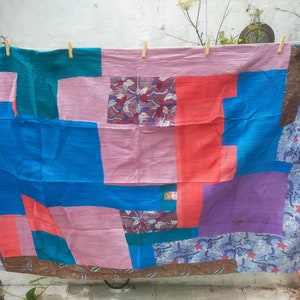 Könnte beinhalten: Eine Patchwork-Decke mit verschiedenen Farben und Mustern, darunter Rosa, Blau, Grün und Braun. Die Decke besteht aus verschiedenen Stoffen, die in einem zufälligen Muster zusammengenäht sind.