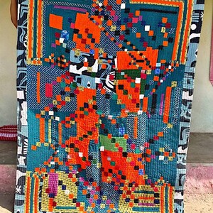 May include: A colorful quilt with a geometric pattern in shades of blue, orange, yellow, green, and black. The quilt is made of patchwork fabric and has a hand-stitched look.