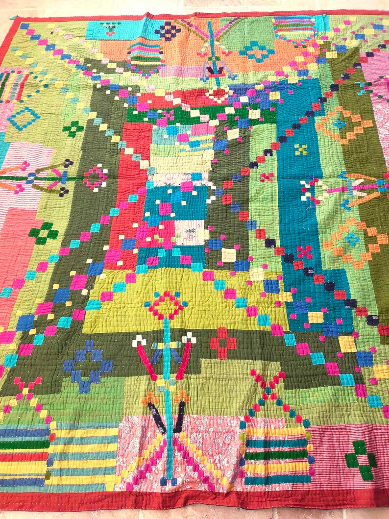 May include: A colorful patchwork quilt with a geometric design. The quilt is made of various fabrics in shades of green, red, blue, yellow, and pink. The quilt is quilted with a simple stitch pattern.