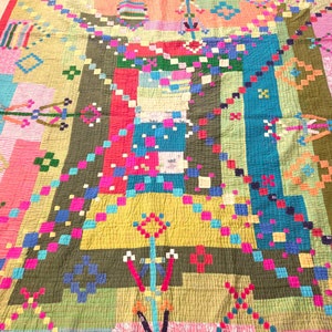 May include: A colorful patchwork quilt with a geometric design. The quilt is made of various fabrics in shades of pink, red, blue, green, and yellow.
