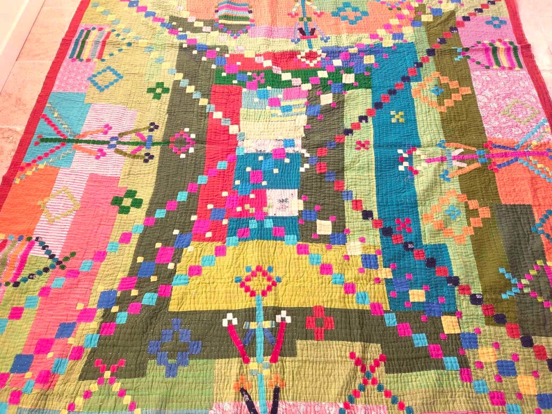 May include: A colorful patchwork quilt with a geometric design. The quilt is made of various fabrics in shades of pink, red, blue, green, and yellow.