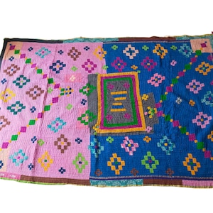 Puede incluir: Una colcha de retazos colorida con un patrón geométrico en tonos de rosa, azul, verde, amarillo y marrón. La colcha está hecha de diferentes telas cosidas juntas para crear un diseño único.