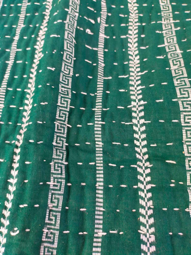 May include: Green fabric with white stitching in a geometric pattern. The fabric has a textured surface.