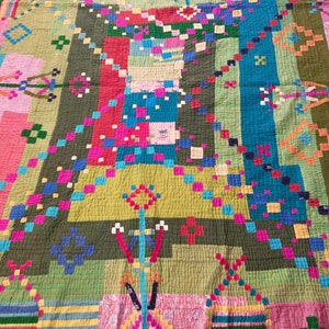 May include: A colorful patchwork quilt with a geometric design. The quilt is made of various fabrics in shades of green, blue, pink, red, and yellow. The quilt is quilted with a simple stitch pattern.