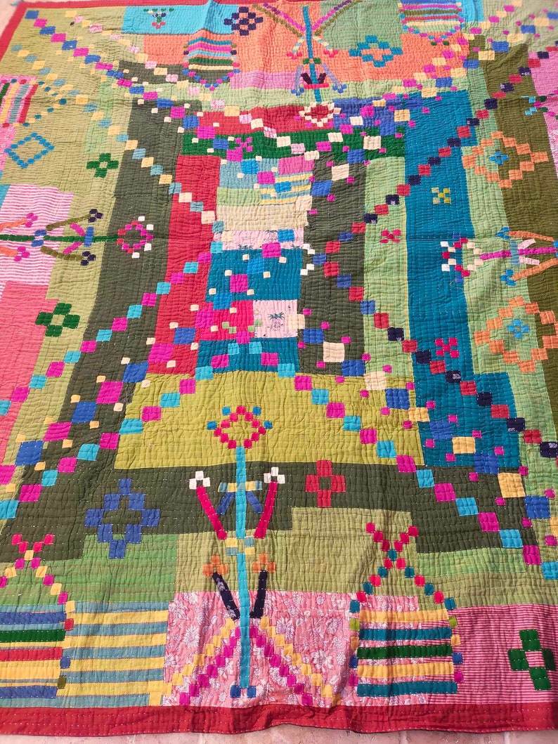 May include: A colorful patchwork quilt with a geometric design. The quilt is made of various fabrics in shades of green, blue, pink, red, and yellow. The quilt is quilted with a simple stitch pattern.