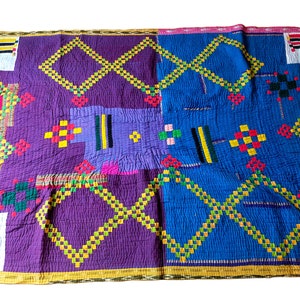 Puede incluir: Una colcha colorida cosida a mano con un patrón geométrico. La colcha está hecha de tela morada, azul, amarilla, verde, roja y blanca. La colcha es de estilo tradicional y es perfecta para agregar un toque de encanto hecho a mano a cualquier hogar.