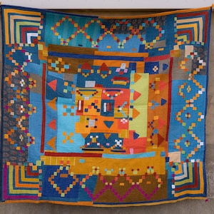 Peut inclure: Une tapisserie colorée à motifs géométriques avec un fond bleu et des accents de jaune, orange, rouge et marron. La tapisserie est en tissu tissé et a une bordure frangée.